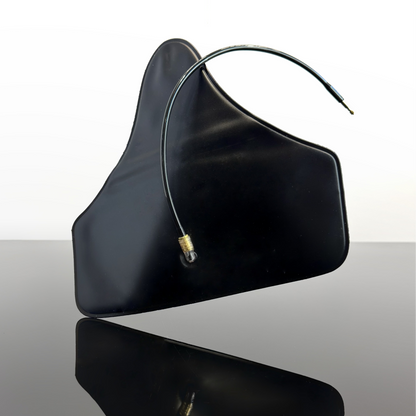 A black curved rubber air bladder with a thin dark tube and small metallic gold nozzle, photographed on a reflective dark surface against a white studio background.