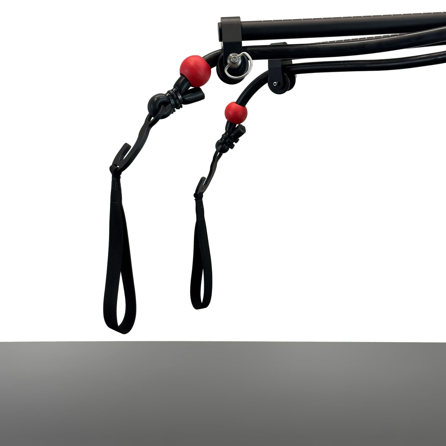 Black metal SlingShot camera mount arms ending with two rubber elastics knotted with red rubber stoppers and metal hooks with loops hanging at the end, shown against a white background above a grey table.