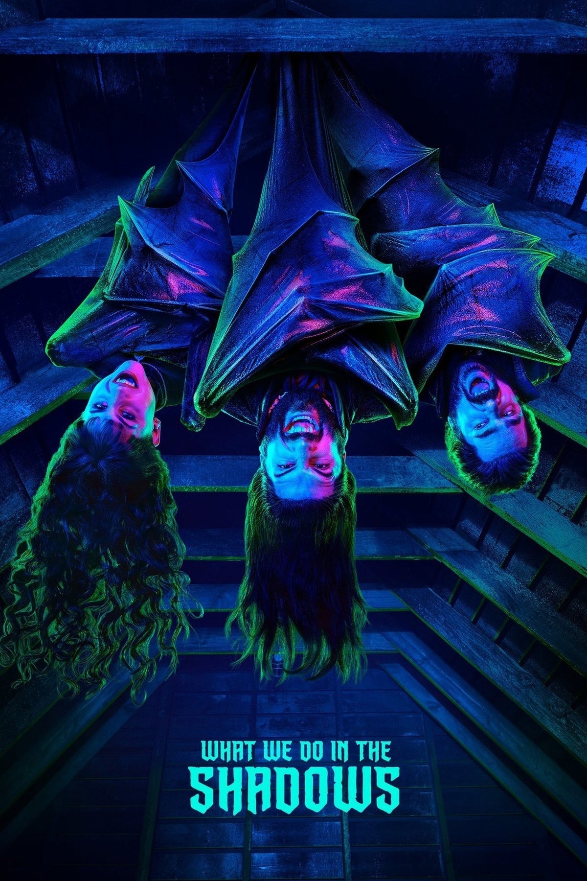 Promotional poster for the FX series 'What We Do in the Shadows' season 1, set against a deep navy blue background. Suspended upside down from the top edge of the frame are three main characters, looking directly at the camera smiling showing their teeth
